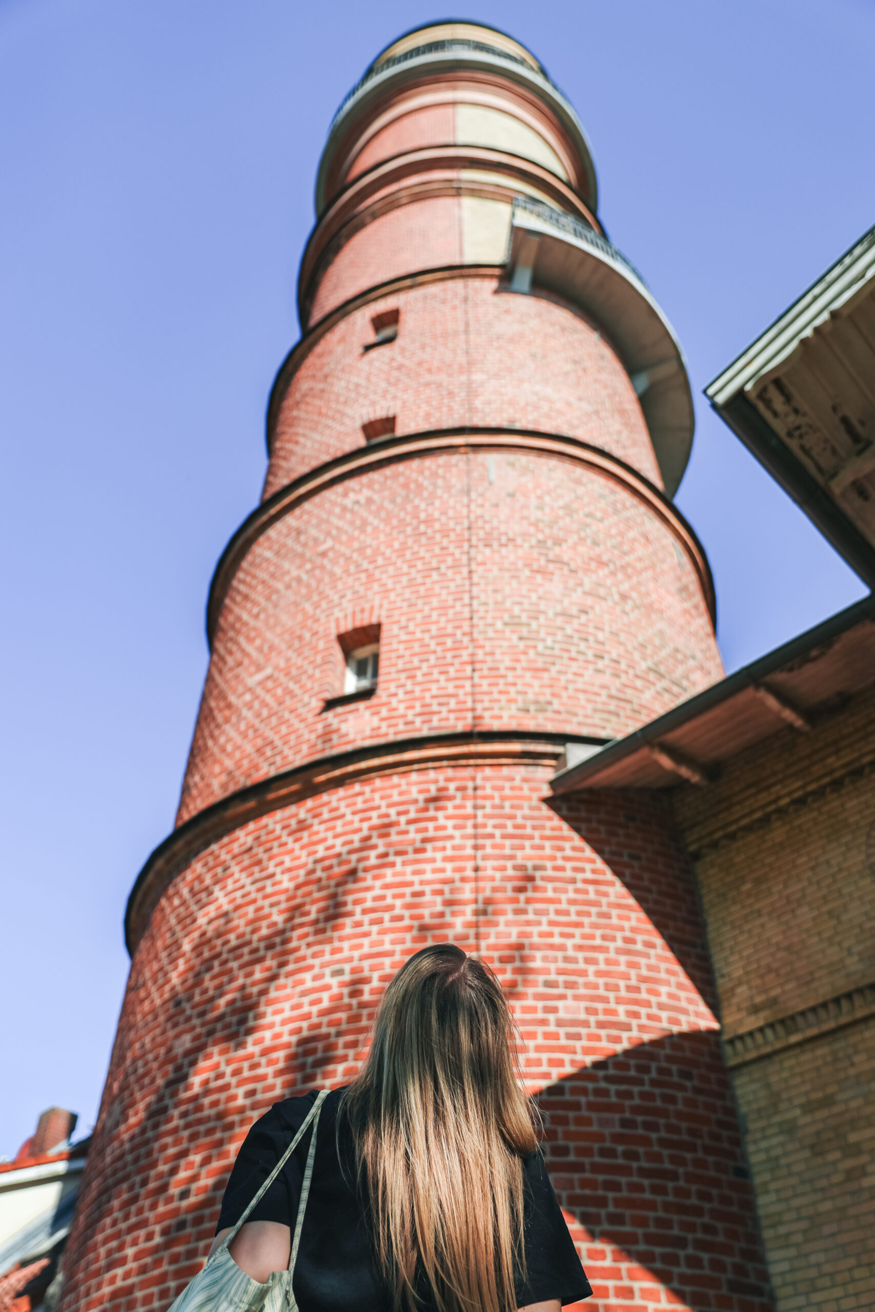 Finja T. blickt hinauf zum ältesten Leuchtturm Deutschlands als erster Tipp für einen Ausflug nach Travemünde