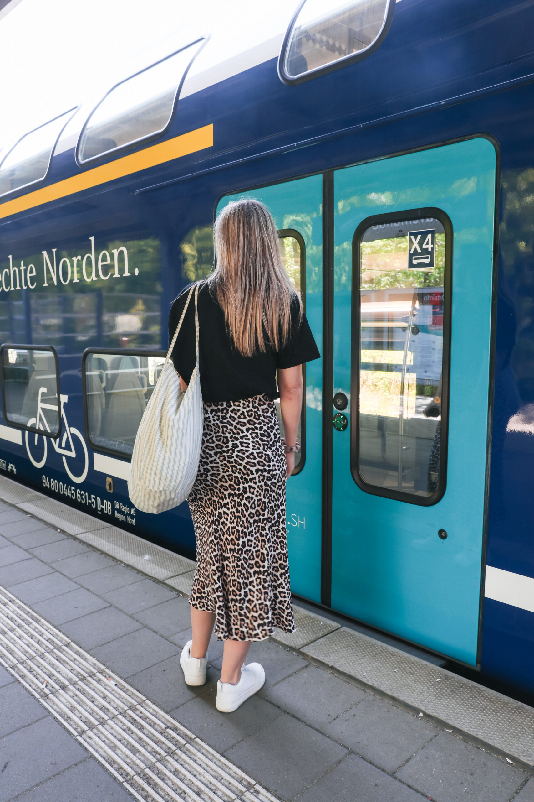 Finja T. vor einem blauen Doppelstockzug der DB Regio Schleswig-Holstein am Bahnhof von Travemünde
