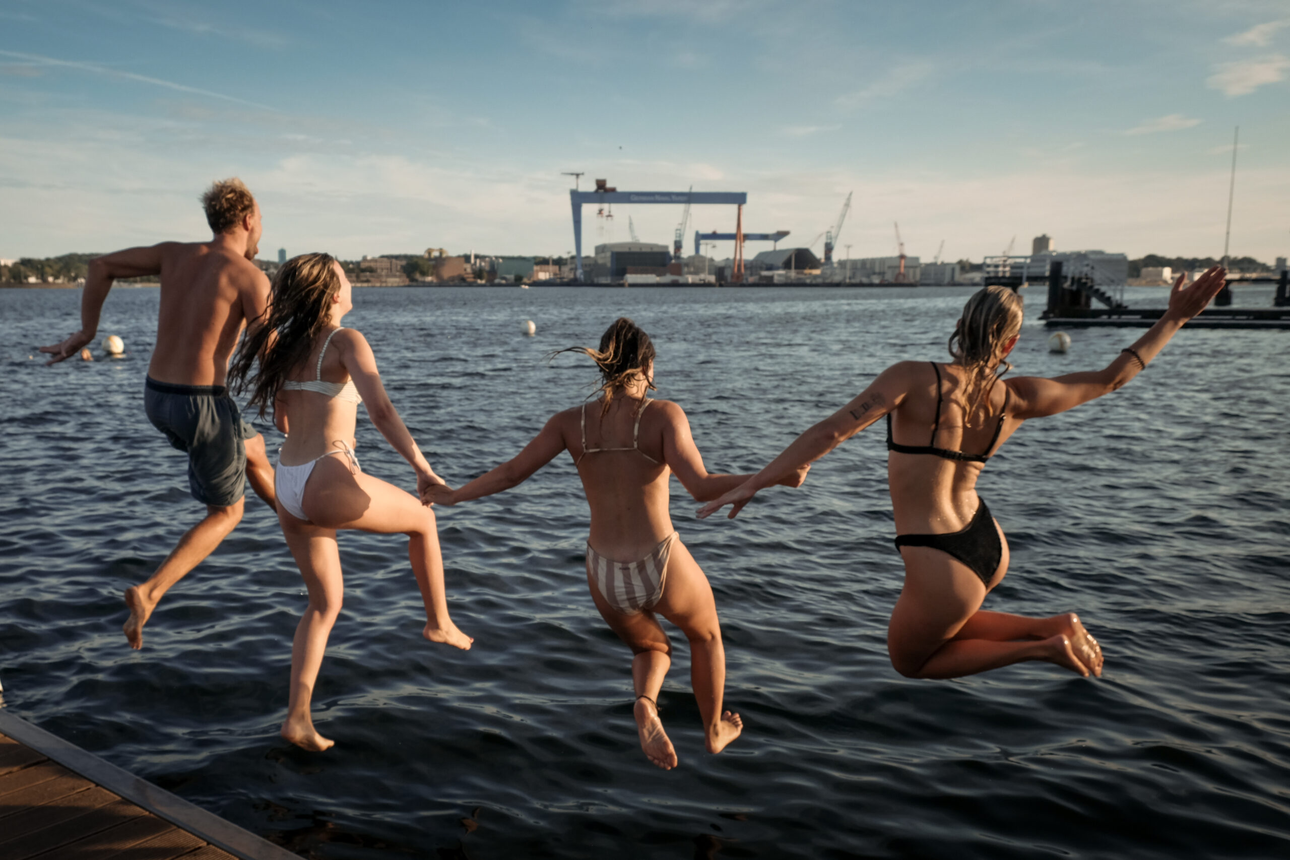 Menschen springen an der Kiellinie in die Förde